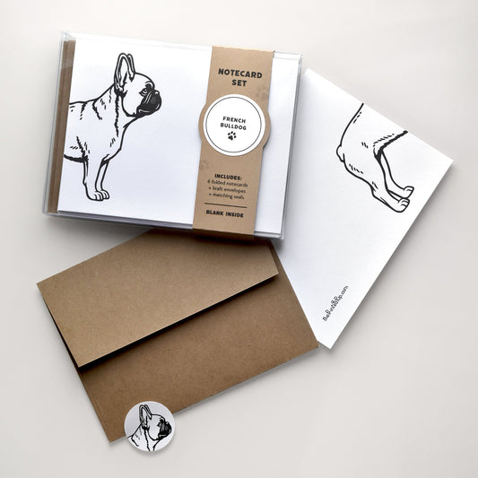 French Bulldog notecard set with clear box packaging, kraft belly band, folded card, kraft envelope, and matching round seal on a warm neutral background.
